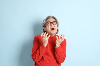 Mavi arka planda duran kıdemli Asyalı adam..