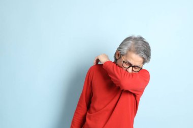 Mavi arka planda duran kıdemli Asyalı adam..