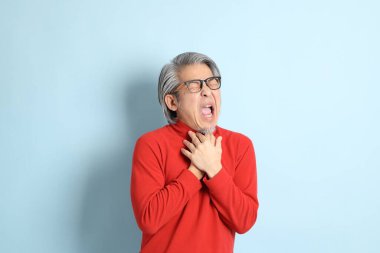 Mavi arka planda duran kıdemli Asyalı adam..