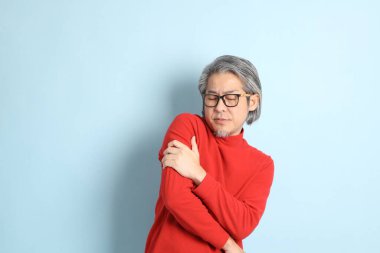 Mavi arka planda duran kıdemli Asyalı adam..