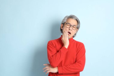 Mavi arka planda duran kıdemli Asyalı adam..