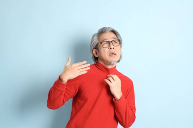 Mavi arka planda duran kıdemli Asyalı adam..