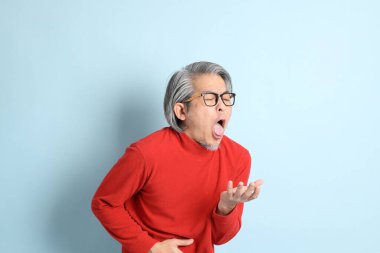 Mavi arka planda duran kıdemli Asyalı adam..