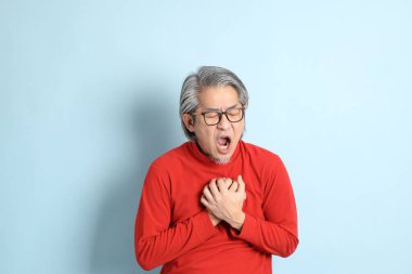 Mavi arka planda duran kıdemli Asyalı adam..