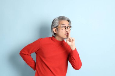 Mavi arka planda duran kıdemli Asyalı adam..