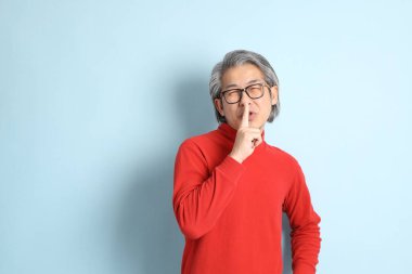 Mavi arka planda duran kıdemli Asyalı adam..