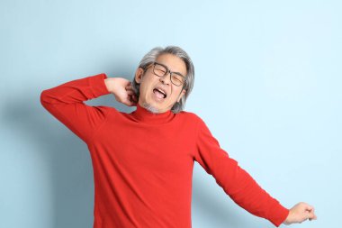 Mavi arka planda duran kıdemli Asyalı adam..