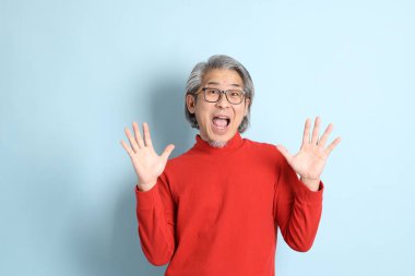 Mavi arka planda duran kıdemli Asyalı adam..