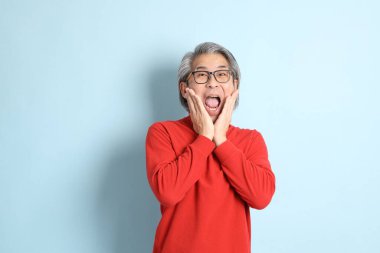 Mavi arka planda duran kıdemli Asyalı adam..