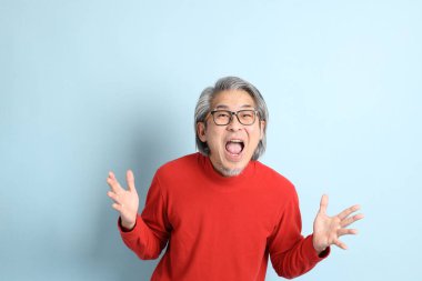 Mavi arka planda duran kıdemli Asyalı adam..