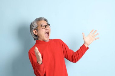 Mavi arka planda duran kıdemli Asyalı adam..