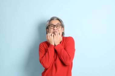 Mavi arka planda duran kıdemli Asyalı adam..