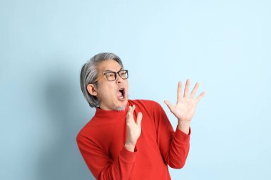 Mavi arka planda duran kıdemli Asyalı adam..