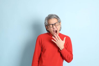 Mavi arka planda duran kıdemli Asyalı adam..