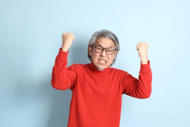 Mavi arka planda duran kıdemli Asyalı adam..