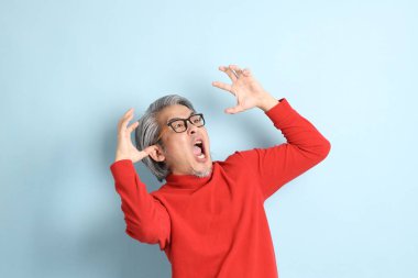 Mavi arka planda duran kıdemli Asyalı adam..