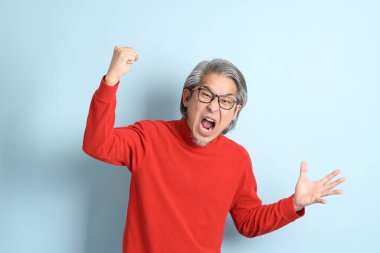 Mavi arka planda duran kıdemli Asyalı adam..