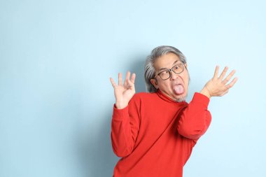 Mavi arka planda duran kıdemli Asyalı adam..