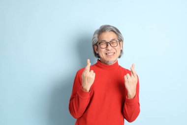 Mavi arka planda duran kıdemli Asyalı adam..