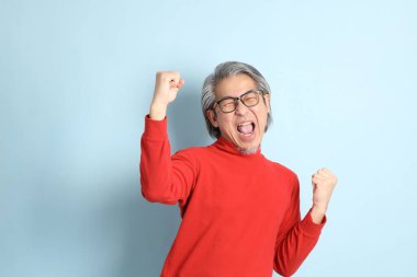 Mavi arka planda duran kıdemli Asyalı adam..