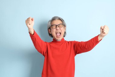 Mavi arka planda duran kıdemli Asyalı adam..