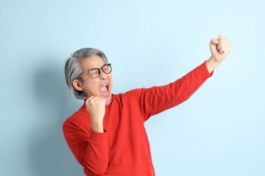 Mavi arka planda duran kıdemli Asyalı adam..