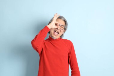 Mavi arka planda duran kıdemli Asyalı adam..