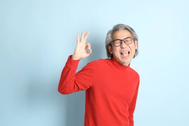 Mavi arka planda duran kıdemli Asyalı adam..