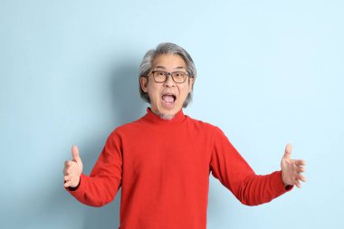 Mavi arka planda duran kıdemli Asyalı adam..