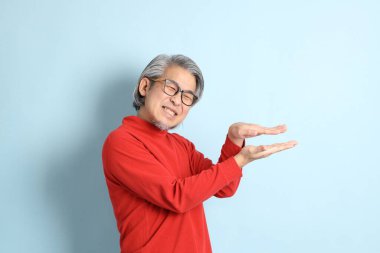 Mavi arka planda duran kıdemli Asyalı adam..