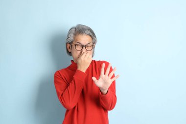 Mavi arka planda duran kıdemli Asyalı adam..