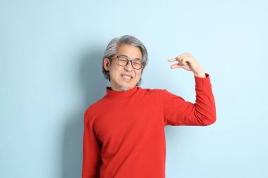 Mavi arka planda duran kıdemli Asyalı adam..