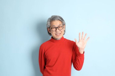 Mavi arka planda duran kıdemli Asyalı adam..