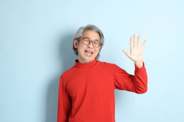 Mavi arka planda duran kıdemli Asyalı adam..