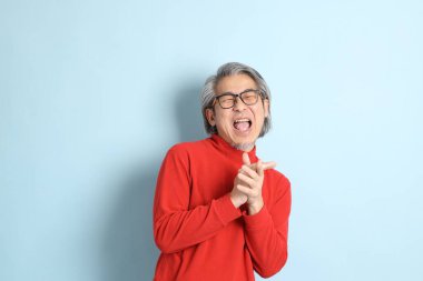 Mavi arka planda duran kıdemli Asyalı adam..