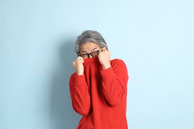 Mavi arka planda duran kıdemli Asyalı adam..