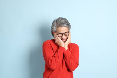 Mavi arka planda duran kıdemli Asyalı adam..