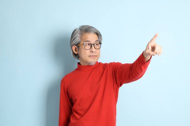 Mavi arka planda duran kıdemli Asyalı adam..