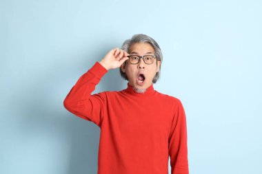 Mavi arka planda duran kıdemli Asyalı adam..