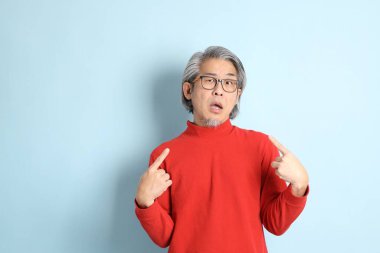 Mavi arka planda duran kıdemli Asyalı adam..