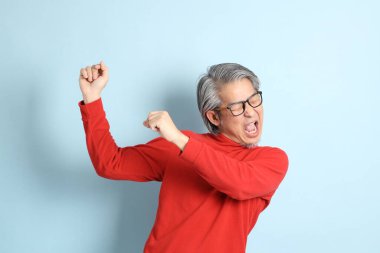 Mavi arka planda duran kıdemli Asyalı adam..