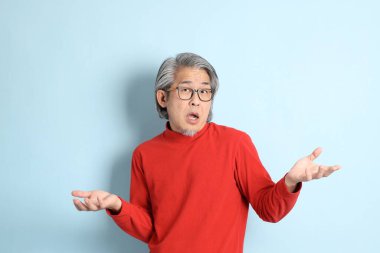 Mavi arka planda duran kıdemli Asyalı adam..