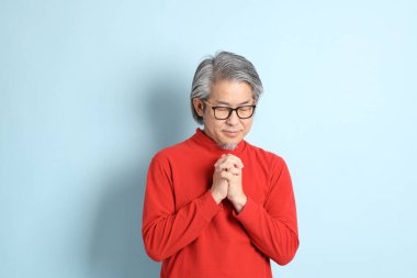 Mavi arka planda duran kıdemli Asyalı adam..