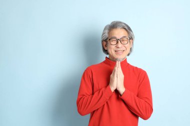 Mavi arka planda duran kıdemli Asyalı adam..