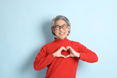 Mavi arka planda duran kıdemli Asyalı adam..