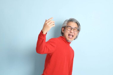 Mavi arka planda duran kıdemli Asyalı adam..