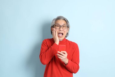 Mavi arka planda duran kıdemli Asyalı adam..