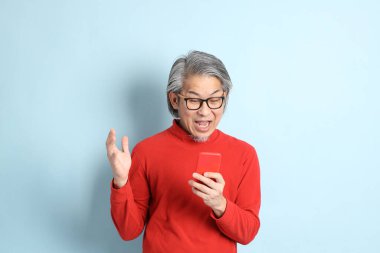 Mavi arka planda duran kıdemli Asyalı adam..