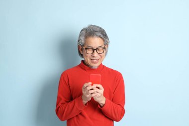 Mavi arka planda duran kıdemli Asyalı adam..