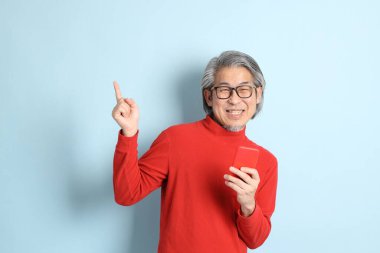 Mavi arka planda duran kıdemli Asyalı adam..